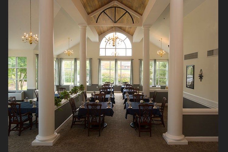 A spacious dining area with elegant columns, large windows, and well-arranged tables and chairs.