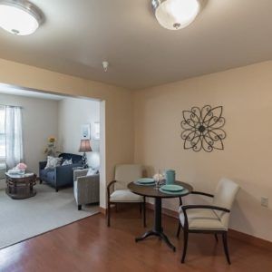 A cozy living and dining area with comfortable seating, featuring a small table with chairs, a sofa, and decorative elements.