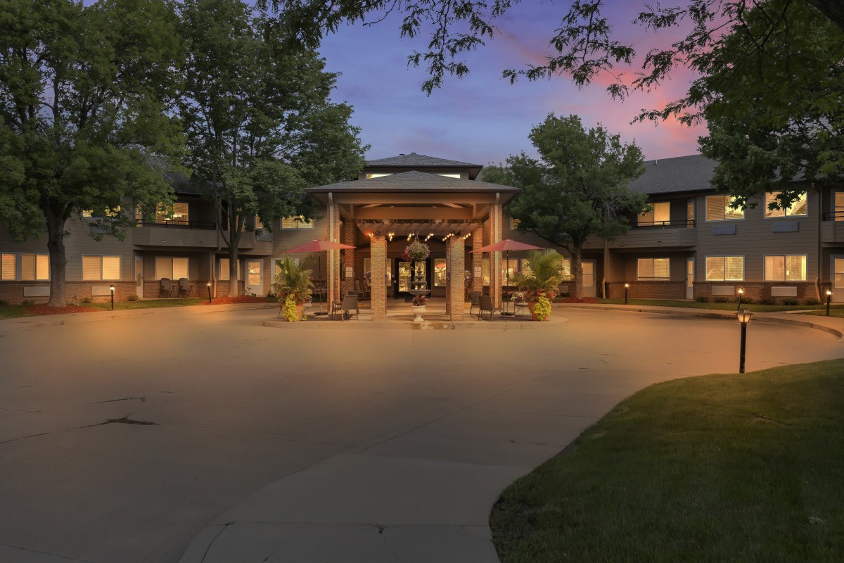 A beautifully lit building entrance surrounded by trees at dusk.