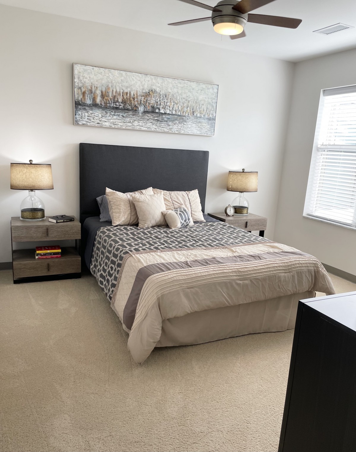 A modern bedroom with a neatly made bed, bedside tables, and decorative lamps.
