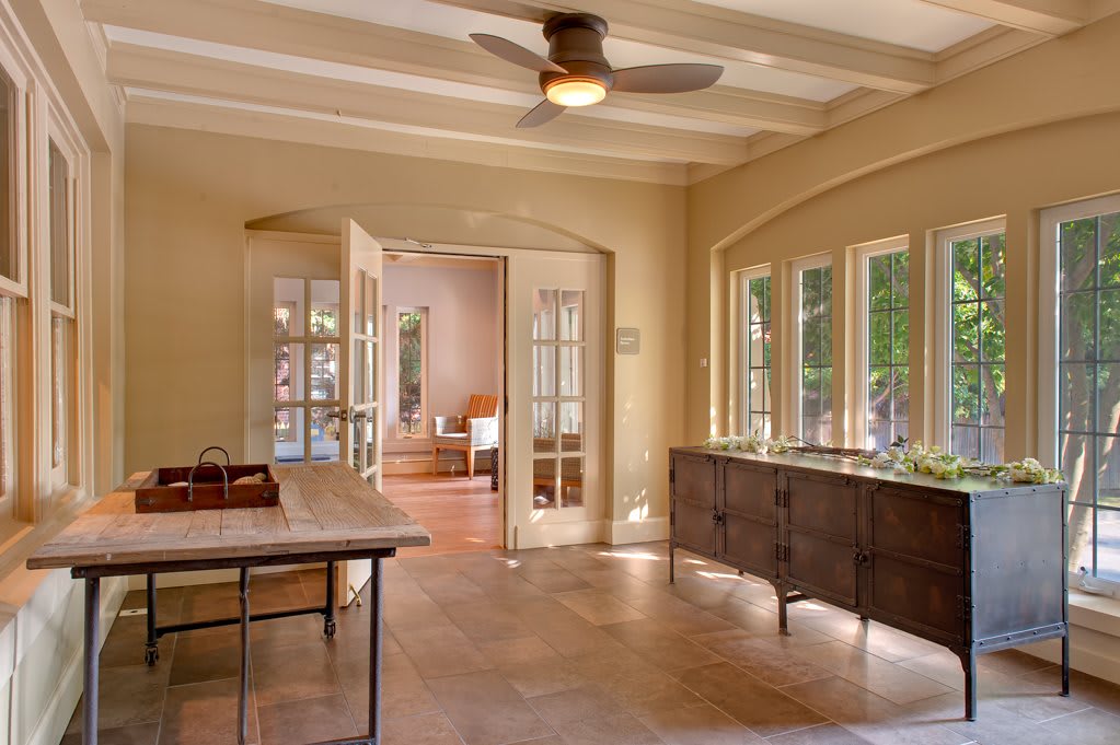 A cozy living space with large windows, a ceiling fan, and stylish furniture.