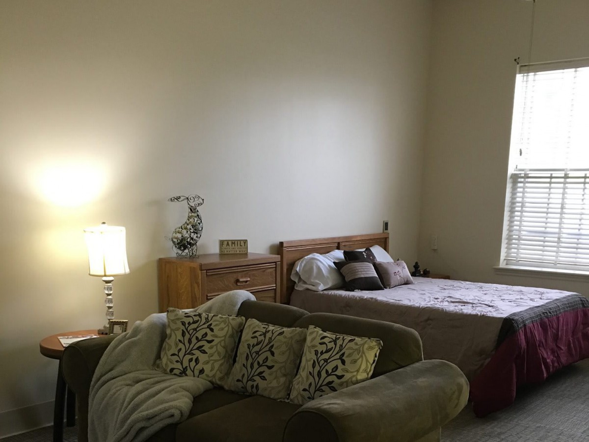 A cozy bedroom with a bed, couch, and lamp.