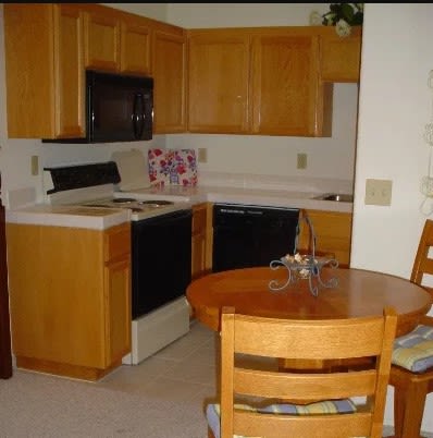 A compact kitchen with wooden cabinets, a dining table, and appliances.