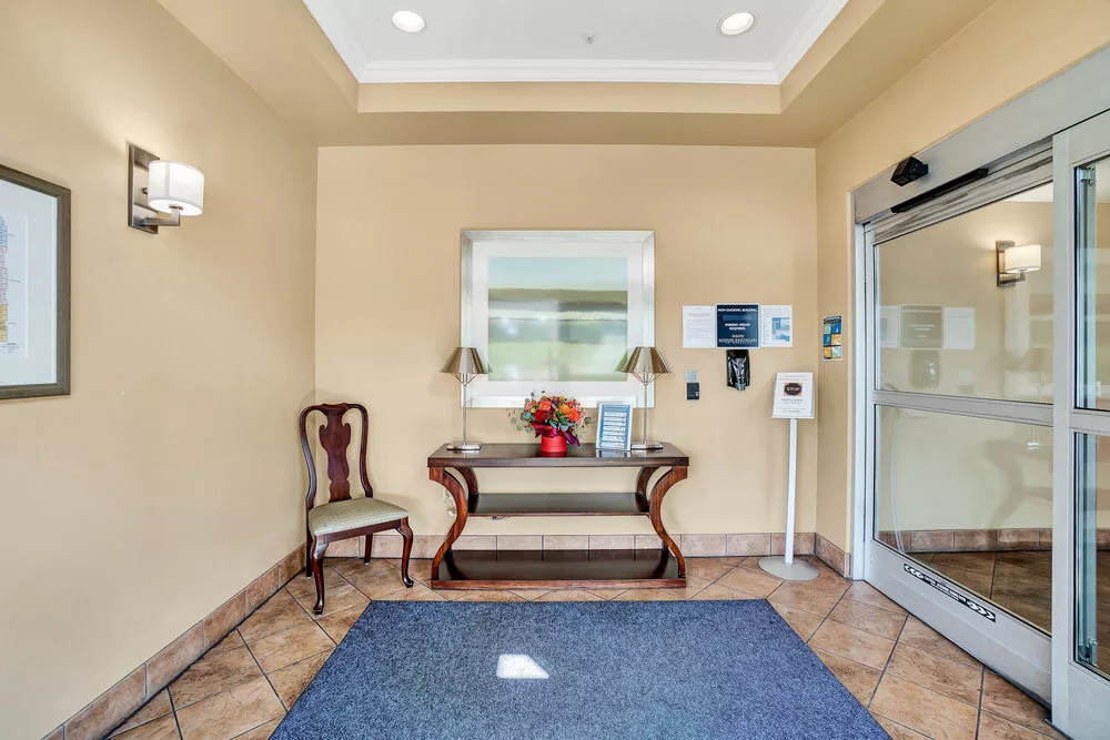 An inviting lobby entrance with a decorative table and chair set beneath a mirror.