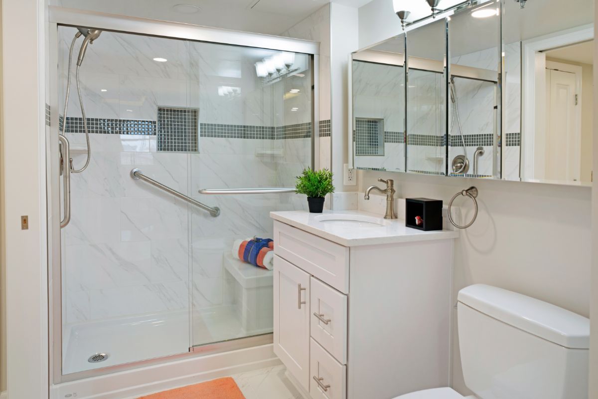 A modern bathroom with a glass-door shower, white vanity, and mirrored cabinets.