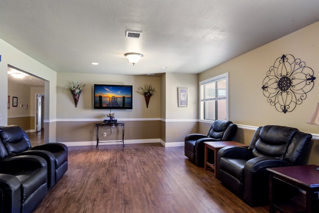 A cozy living room with leather chairs, a television, and a hardwood floor.