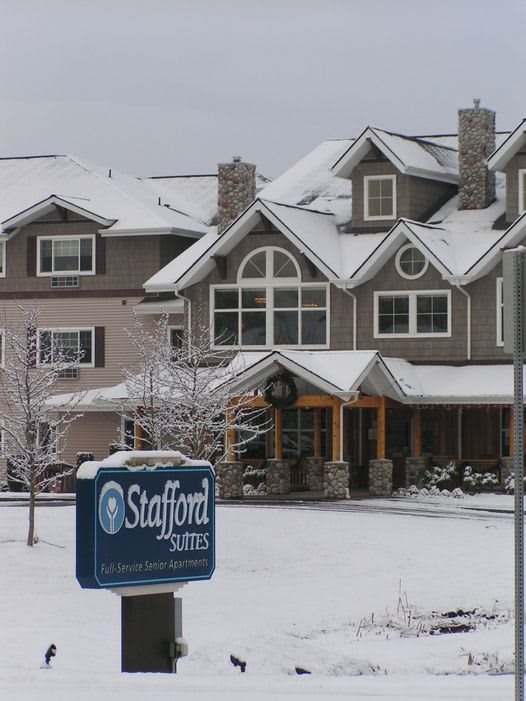 Snow-covered residential building with a visible sign during winter.