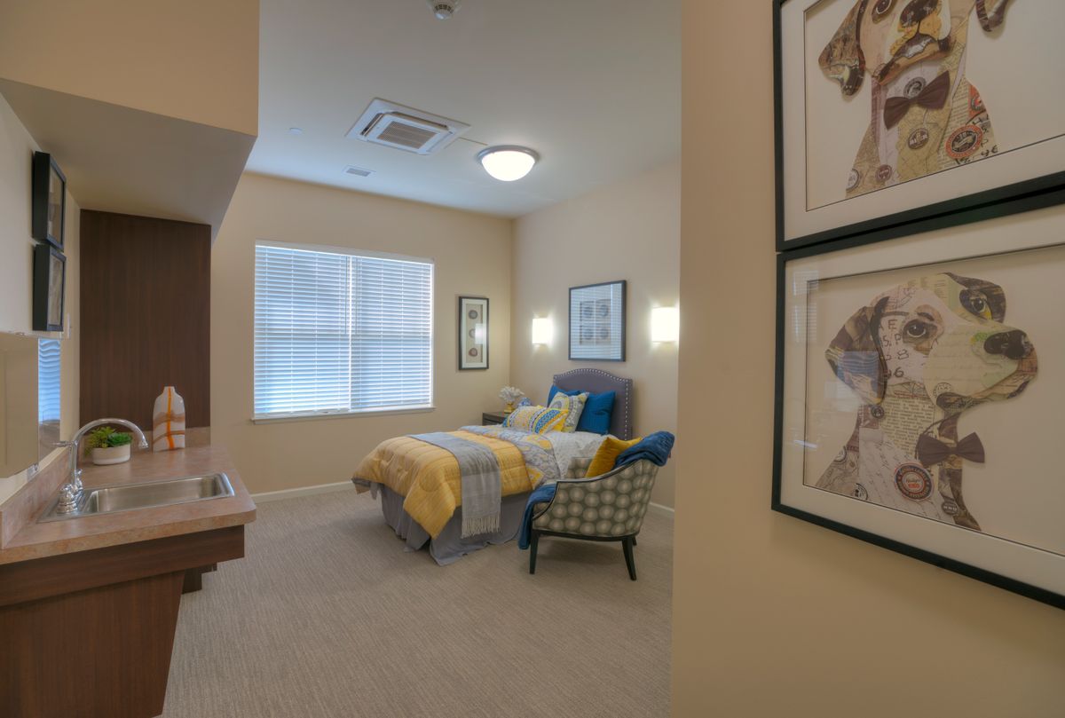 A cozy bedroom with a neatly made bed, decorative pillows, and framed art on the walls.