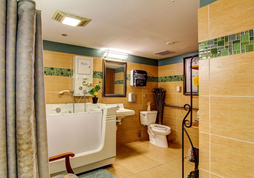 An accessible bathroom featuring a walk-in tub, toilet, and sink.