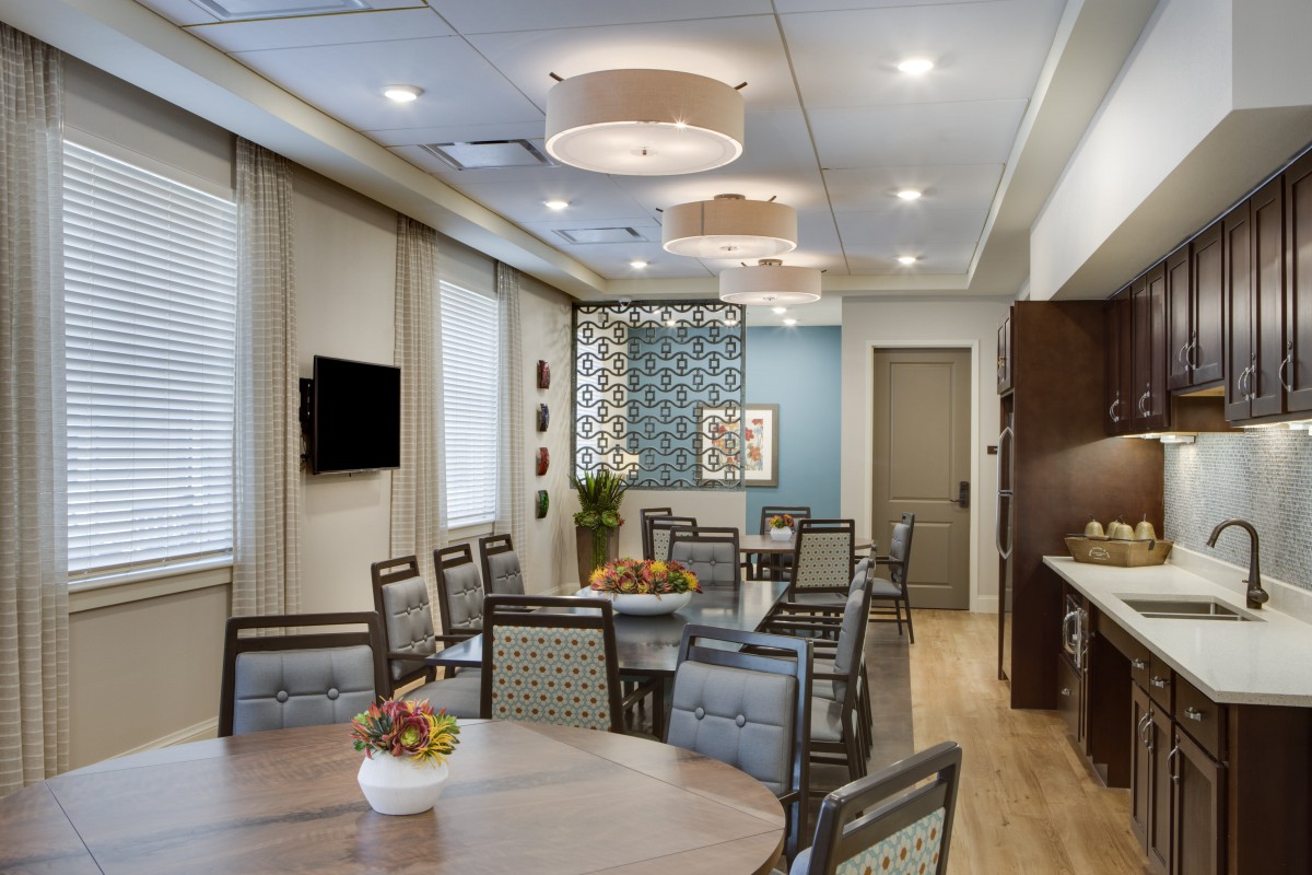 A modern conference room with tables and chairs arranged for a meeting, featuring stylish lighting and decor.