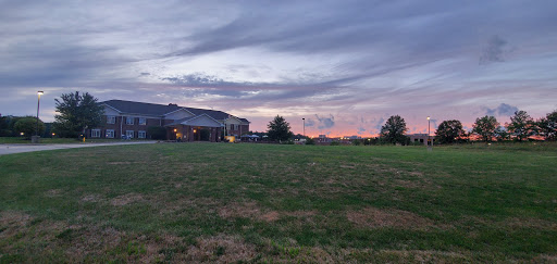 A beautiful sunset casts warm hues over a grassy field with a distant building.