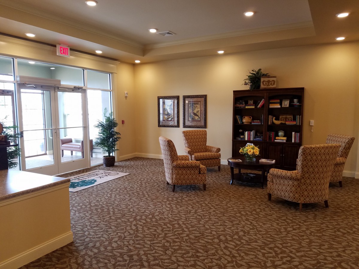 A cozy lobby seating area with chairs, a bookshelf, and decorative elements.