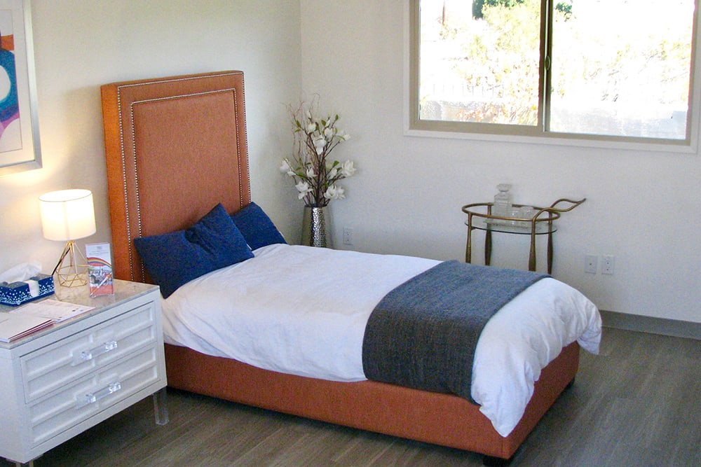 A neatly arranged bedroom with a bed, pillows, and modern decor.