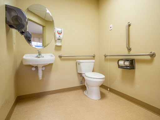 A clean and accessible restroom featuring a toilet, sink, and safety handrails.