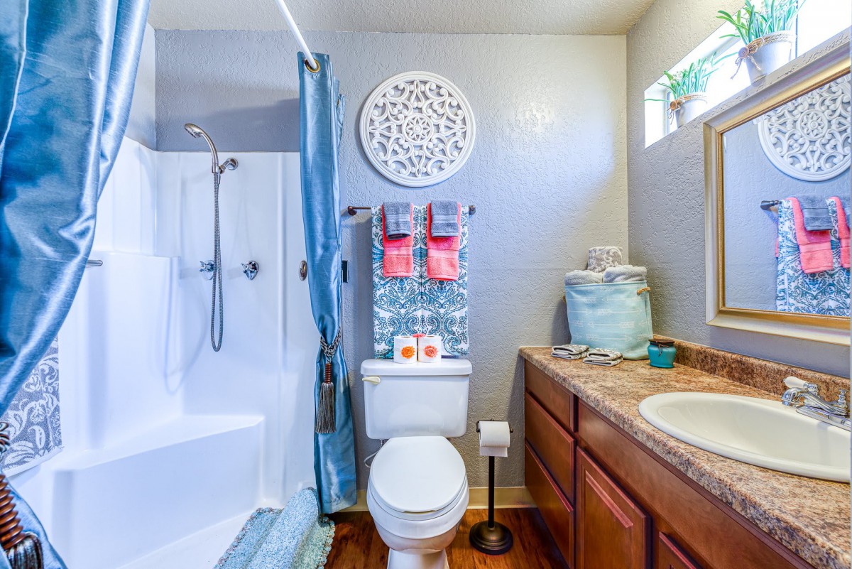 A well-organized bathroom with a shower, toilet, and sink, featuring decorative elements and neatly arranged towels.