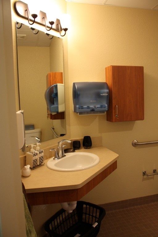 A clean and organized bathroom with a sink, mirror, and paper towel dispenser.