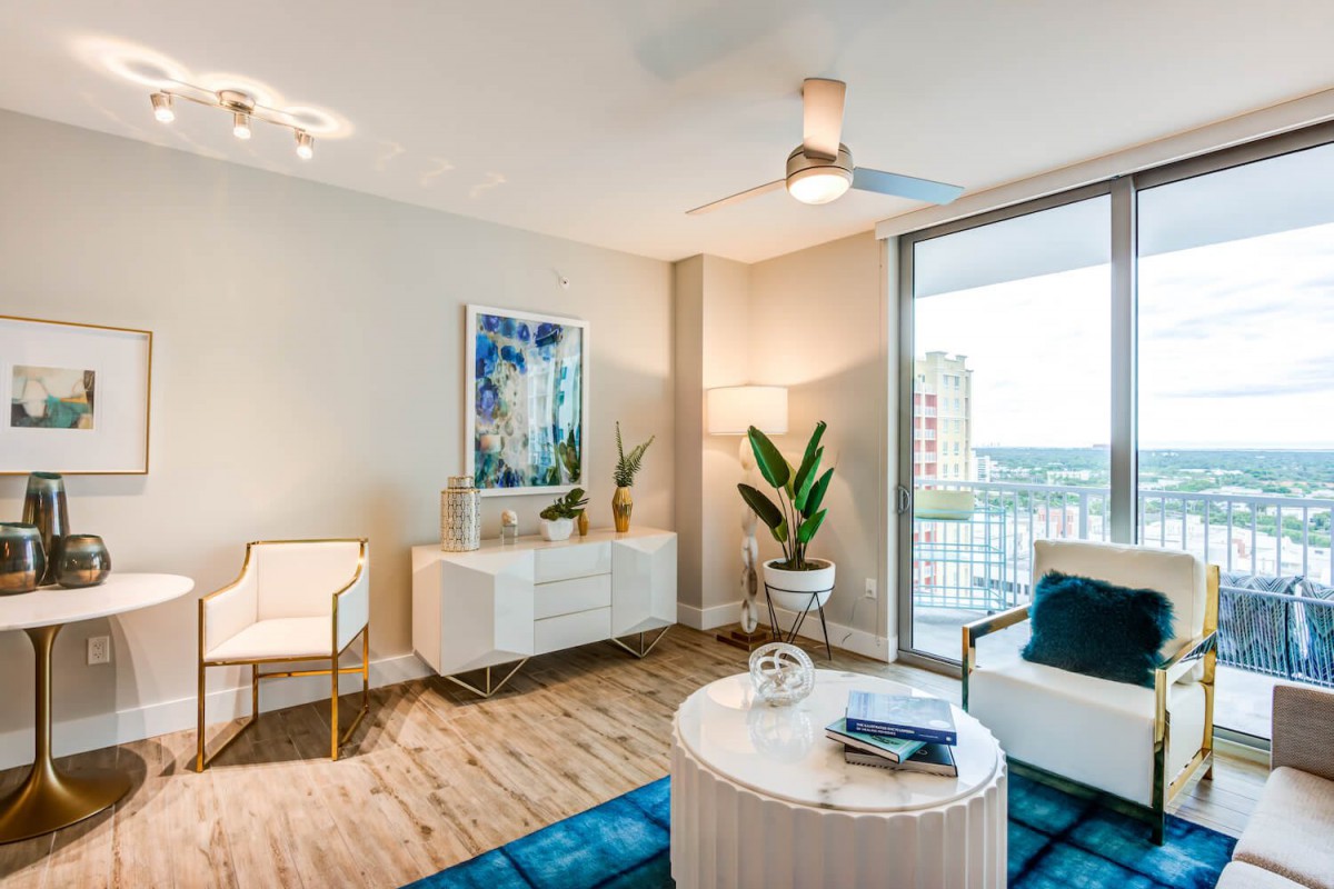 A modern living room featuring stylish furniture, artwork, and a balcony view.