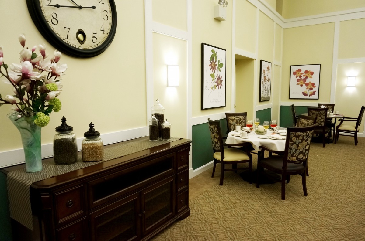 A cozy dining area with a wall-mounted clock, artwork, and a neatly set table.