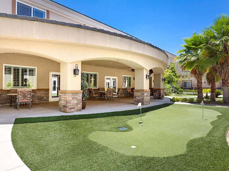A backyard with a covered patio area and a golf putting green.