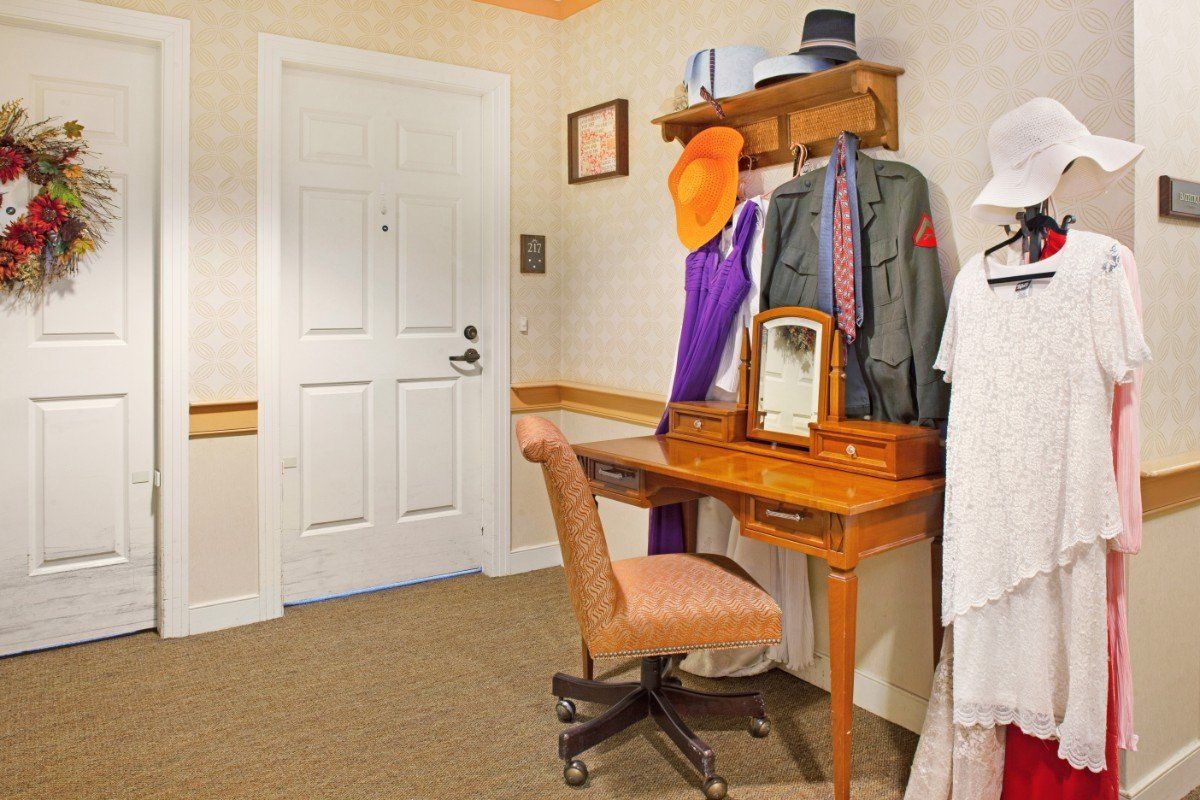 A cozy dressing room with a vanity table, mirror, and clothing accessories.