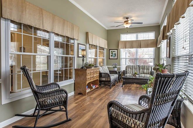 A cozy sunroom filled with wicker furniture and natural light streaming through large windows.
