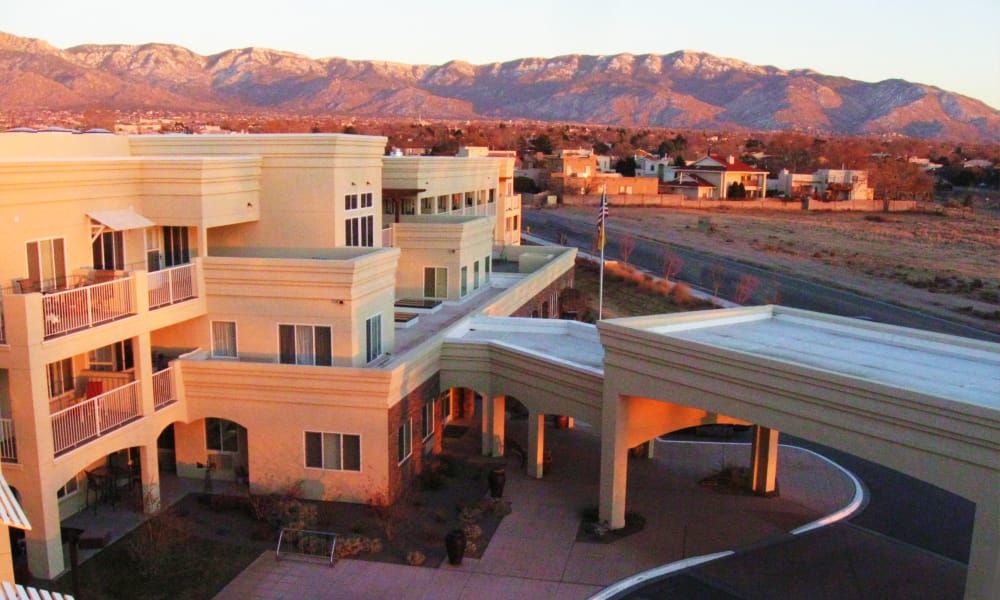 A modern building with a mountain range in the background during sunset.