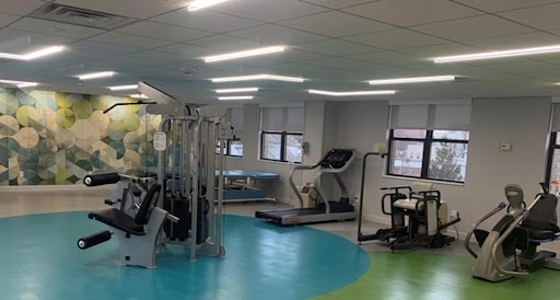 A well-equipped gym featuring various exercise machines and a vibrant floor design.