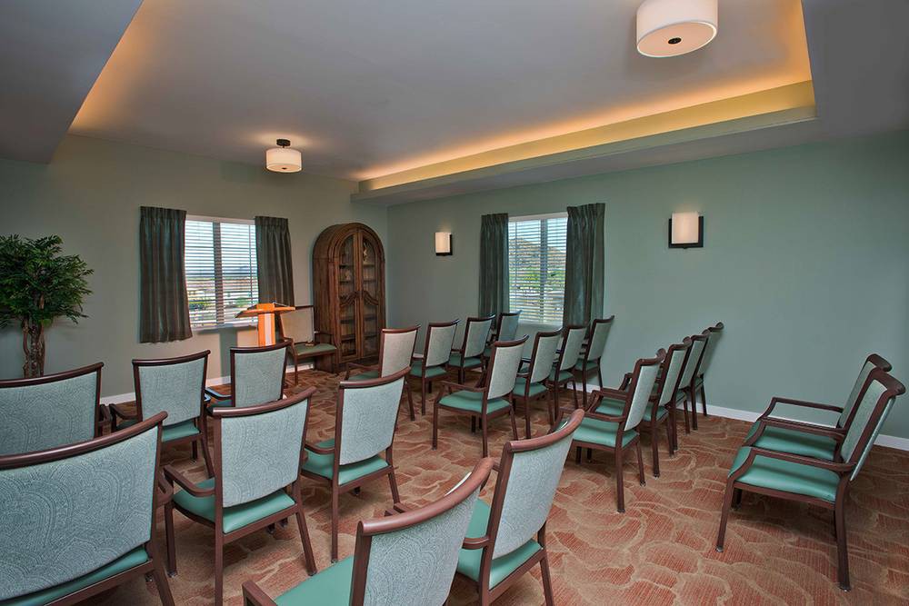 A well-arranged conference room with chairs facing a small podium and large windows allowing natural light.