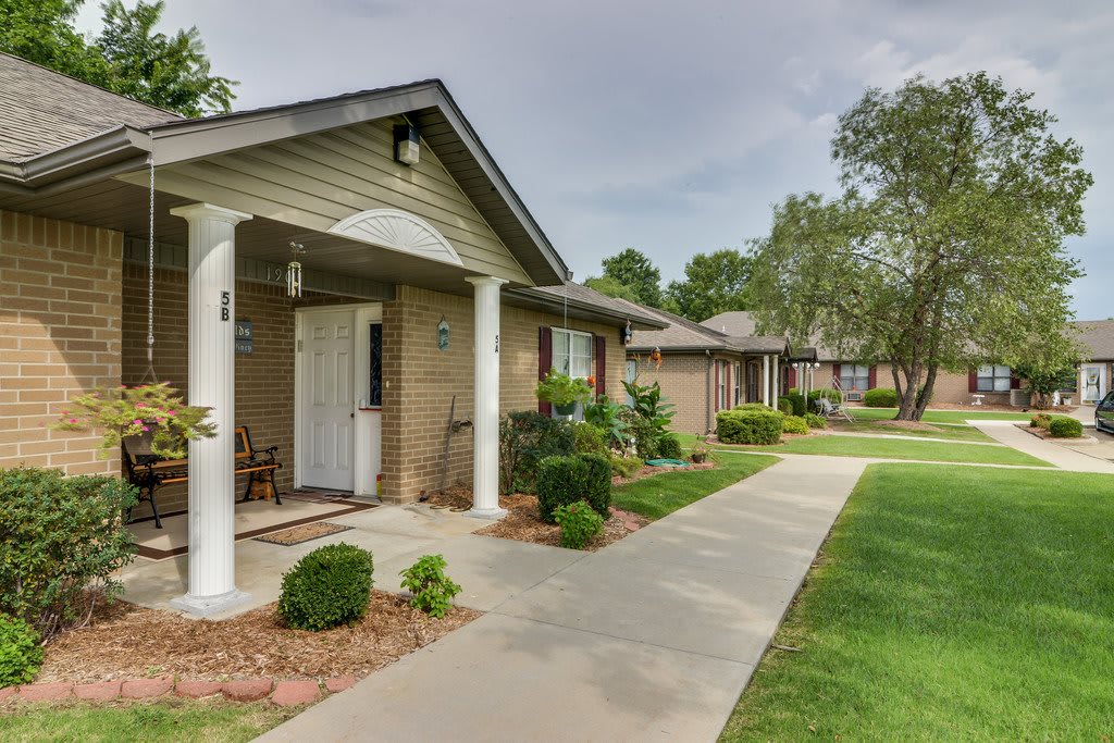 A row of single-story residential houses with well-maintained lawns and a paved pathway.