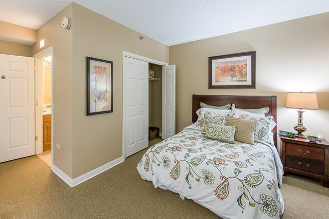 A cozy bedroom with floral bedding, framed artwork, and a small closet.