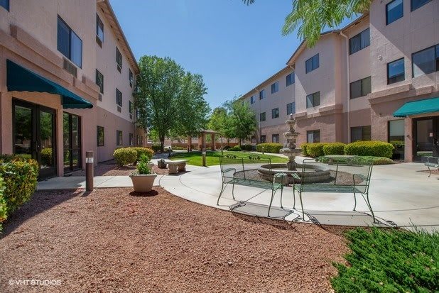 A peaceful courtyard with seating areas surrounded by buildings and greenery.