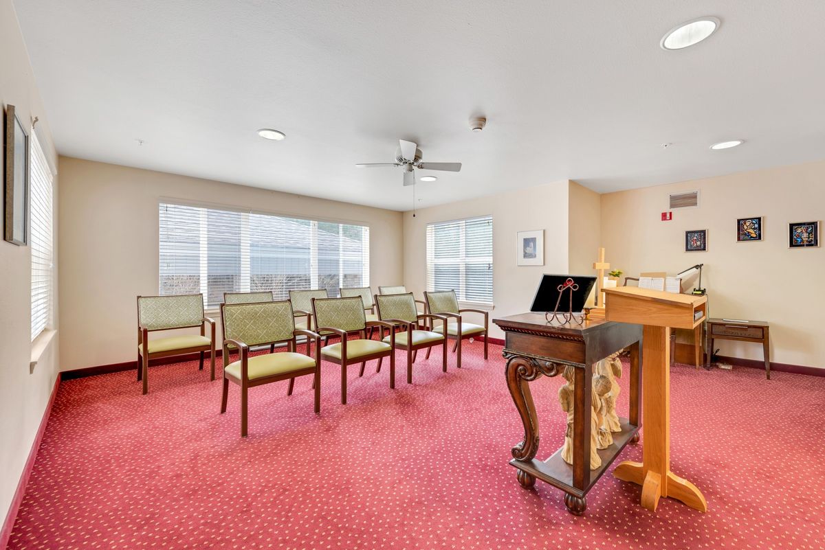 A small meeting room with chairs and a podium on a red carpet.