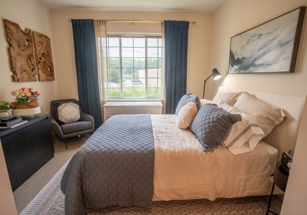 A cozy bedroom with a well-made bed, blue curtains, and elegant decor.