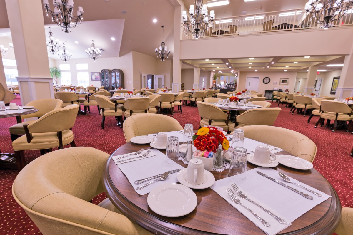 A spacious, elegantly furnished dining room with neatly set tables and soft lighting.