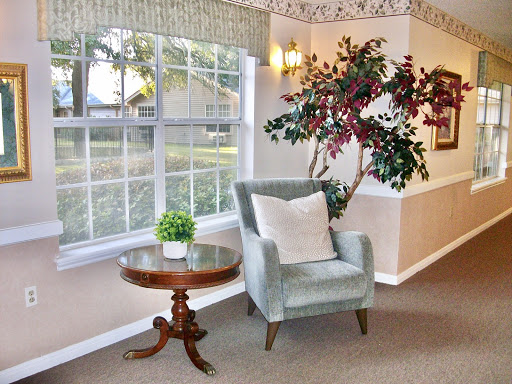 A cozy corner featuring a green armchair, a small wooden table, and a decorative plant by the window.