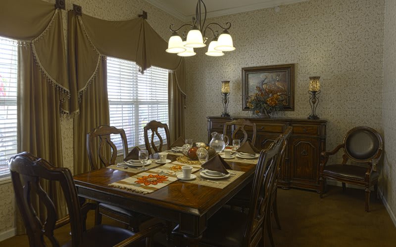 A beautifully set dining room with an elegant table and chairs, adorned by a chandelier, ready for a meal.