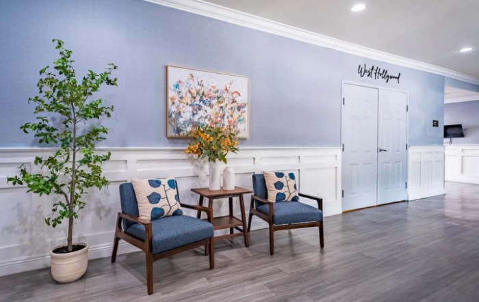 A cozy waiting area with two chairs, a small table with a flower vase, and wall art.