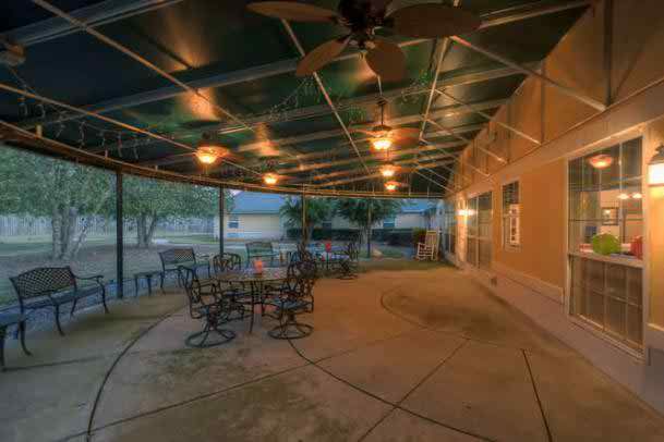 A tranquil backyard patio with a covered seating area illuminated by warm evening lights.