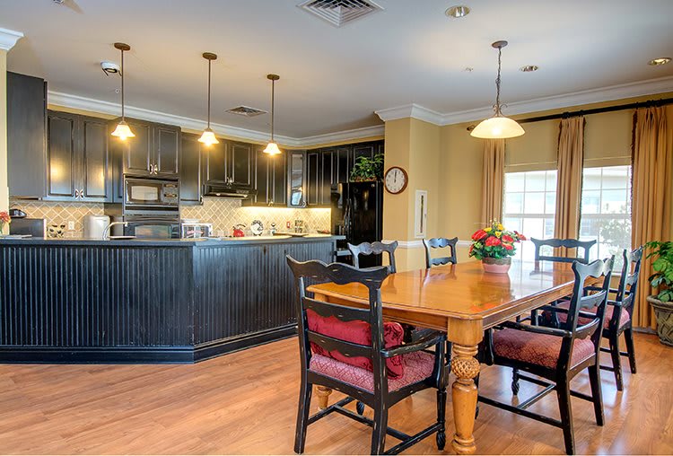 A cozy kitchen and dining area with dark cabinets, a wooden table, and pendant lighting.