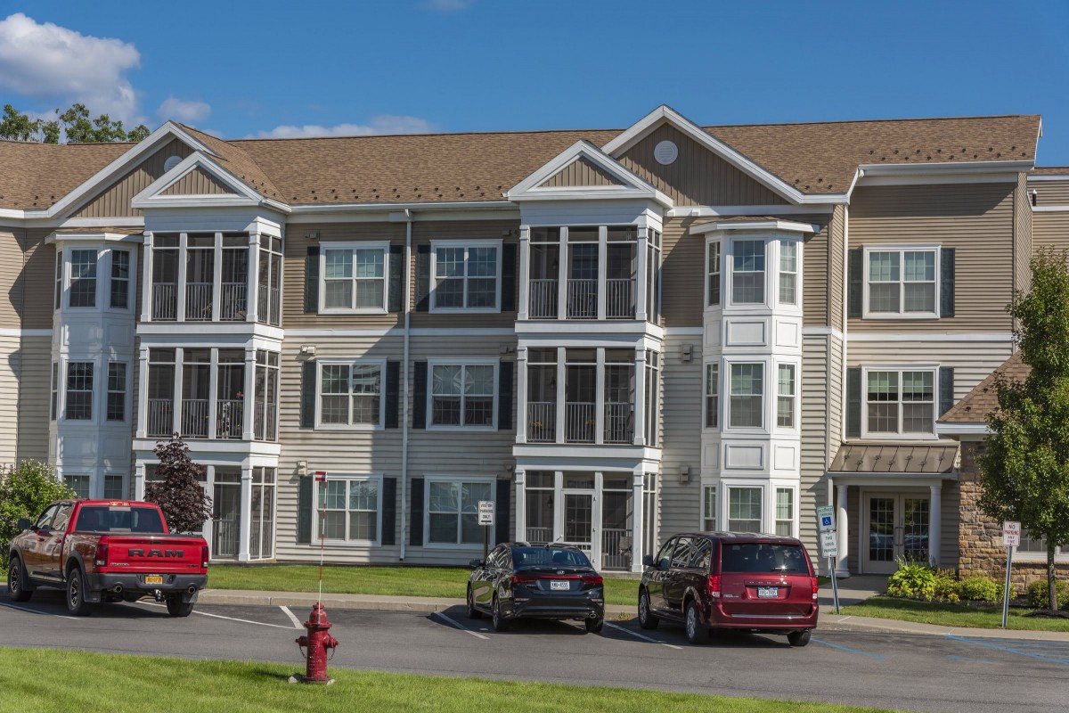 A modern apartment building with a parking lot in a suburban area.