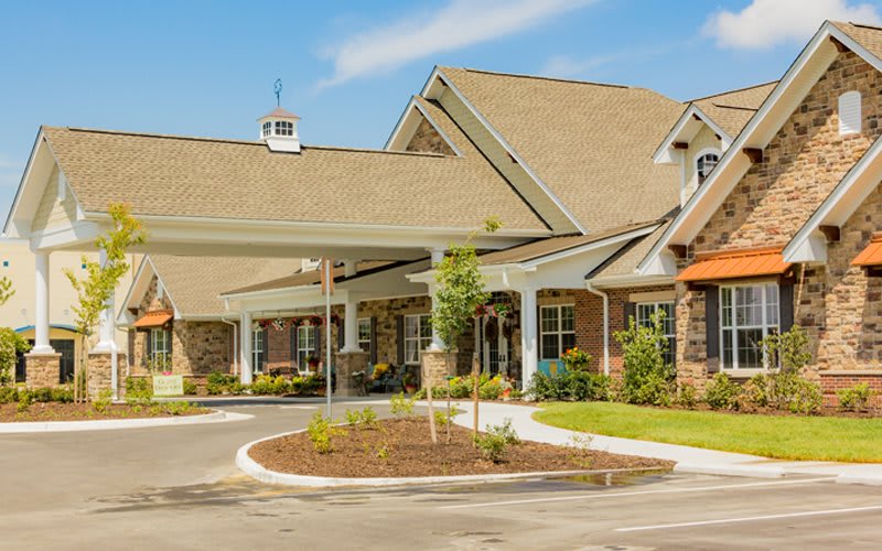 A modern residential building with a landscaped entrance on a sunny day.