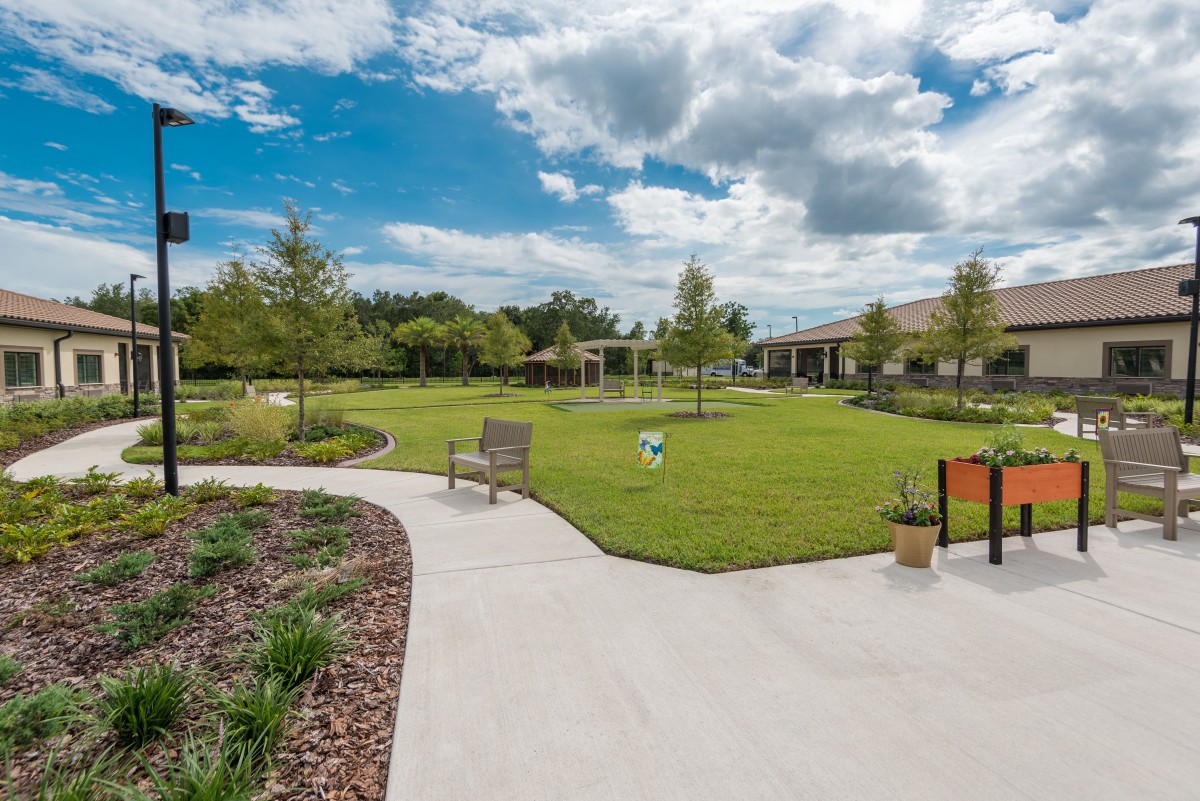 A scenic view of a landscaped garden with pathways, benches, and a partly cloudy sky.