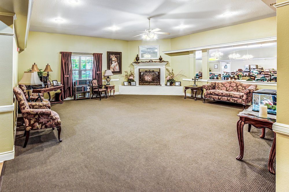A spacious living room with traditional decor, featuring a central fireplace and comfortable seating arrangements.