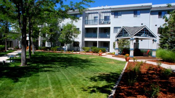 A well-maintained apartment complex with lush green lawns and surrounding trees.