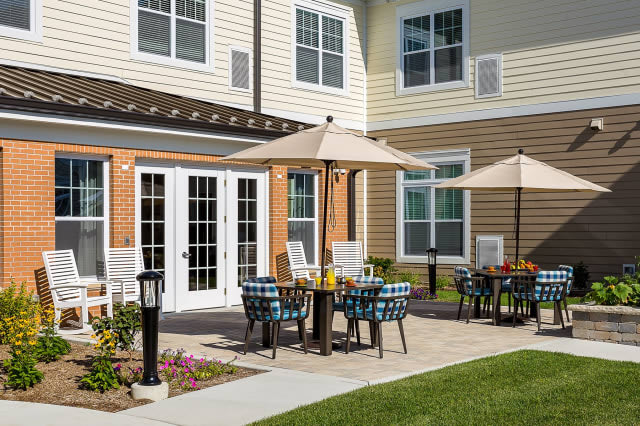 Outdoor seating area with tables and umbrellas on a patio outside a building.