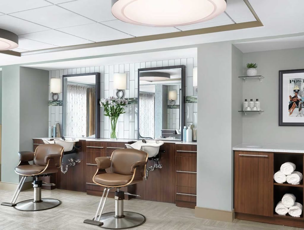 A modern barbershop interior with stylish chairs and large mirrors.
