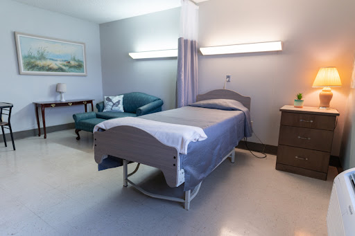 A well-lit and organized patient room in a hospital, featuring a bed and comfortable seating.