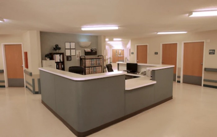 A reception area with a large desk, computers, and organized shelving.