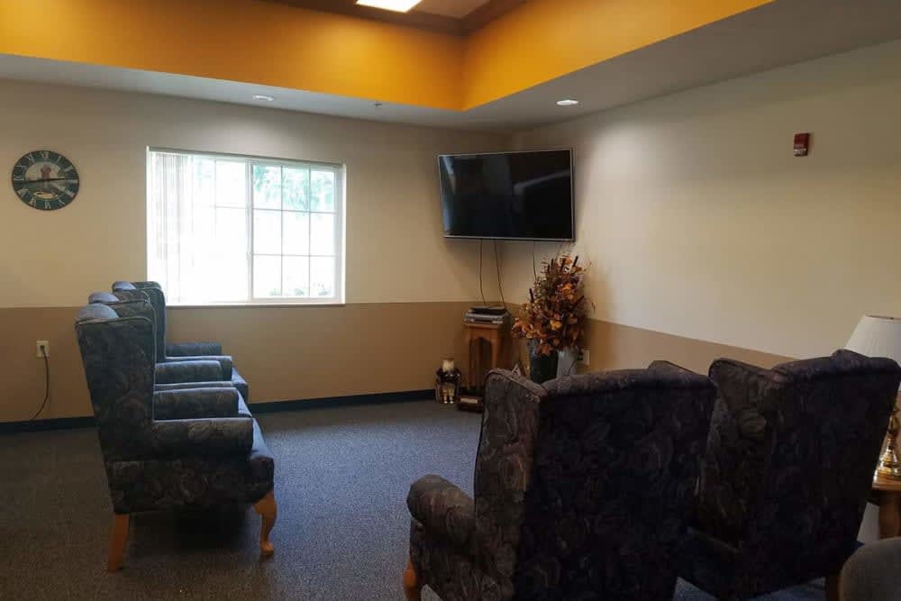A cozy waiting room with chairs arranged around a TV and a window letting in natural light.