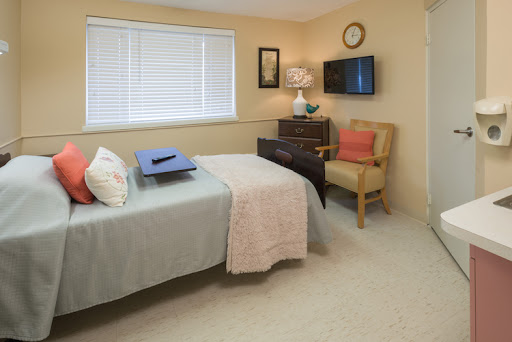 A cozy bedroom featuring a neatly made bed, a comfortable chair, and decorative elements.